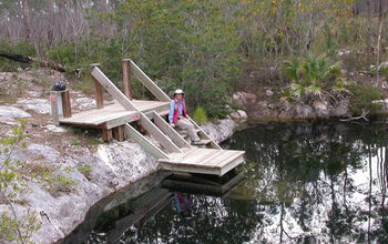 person sitting next to a lake formed in a flooded sinkhole